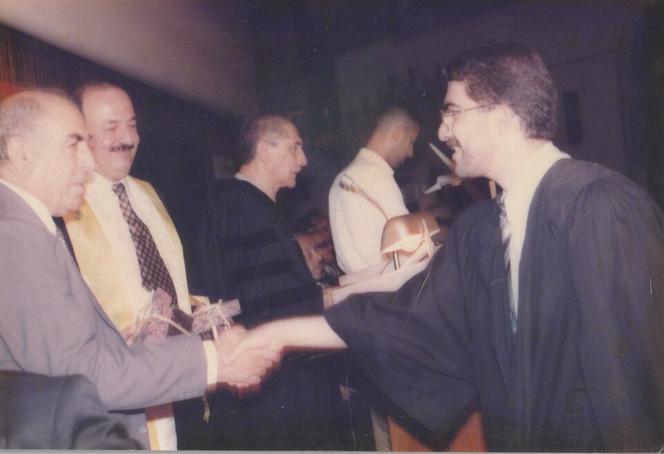 عزيز محمود شكري أثناء تقديم جائزة، إلى جانب محمد الراوي، في كلية طب بغداد عام 2000؛ بحسب وصف المصدر.